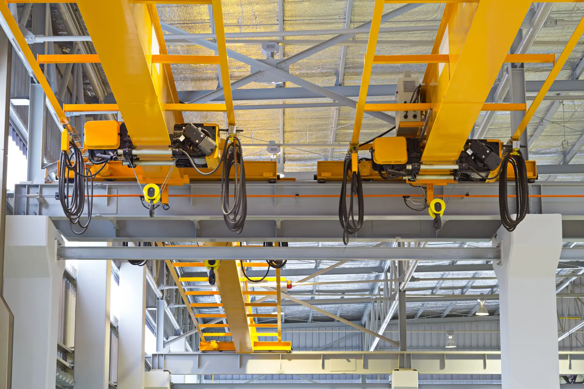 Overhead crane and hook inside factory building for lifting work.