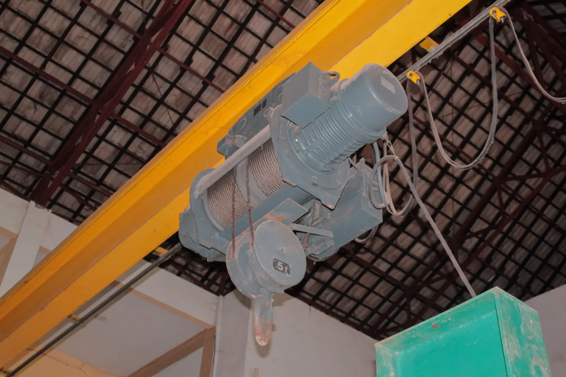 Industrial overhead crane hoist mechanism with wire rope and hook in a warehouse