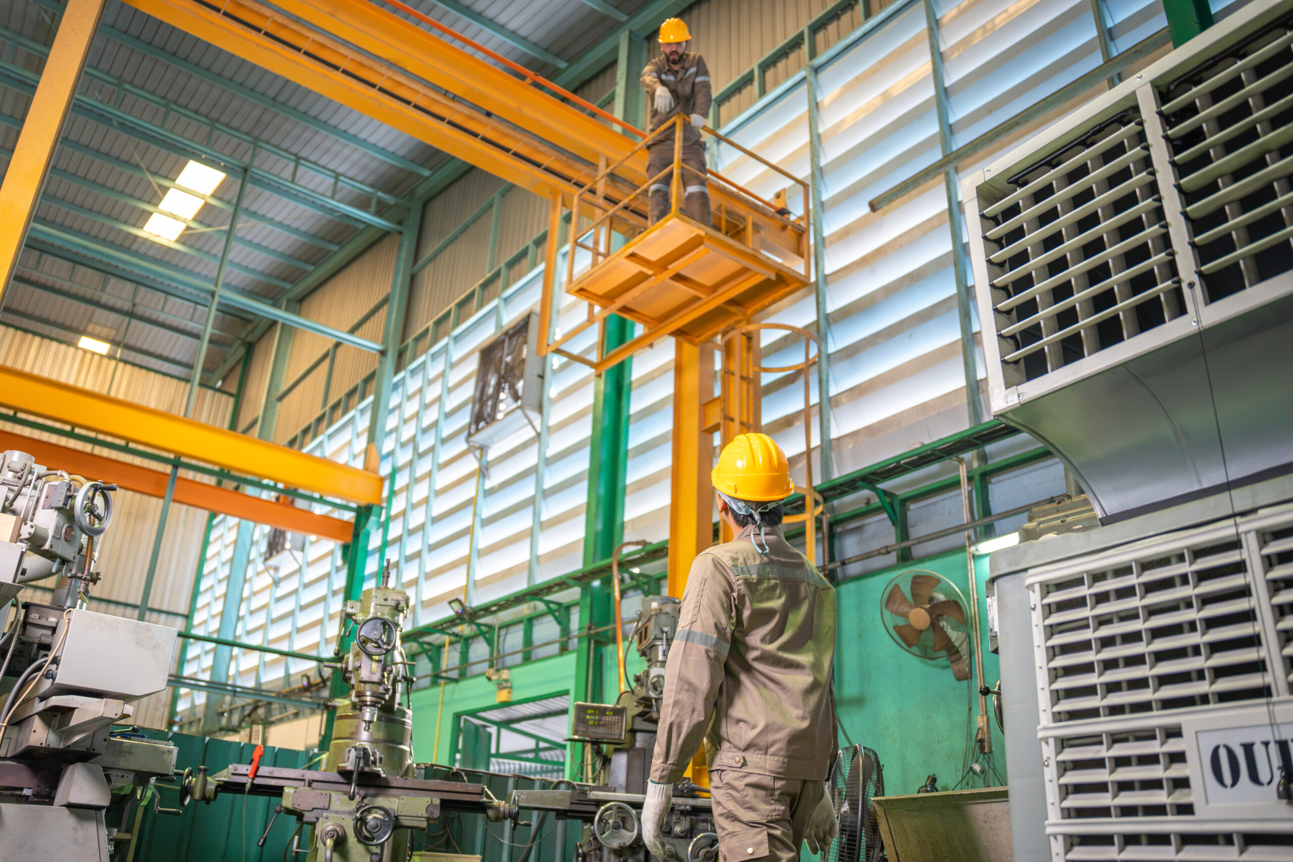 Factory workers operating crane and machinery in industrial plant, Industrial technician working at height on overhead crane in factory, Manufacturing plant interior with workers and heavy machinery